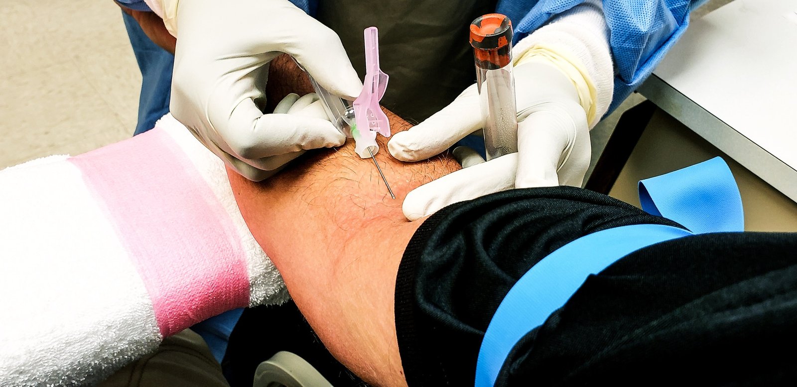 Retired senior getting venipuncture in hospital laboratory as part of yearly physical.